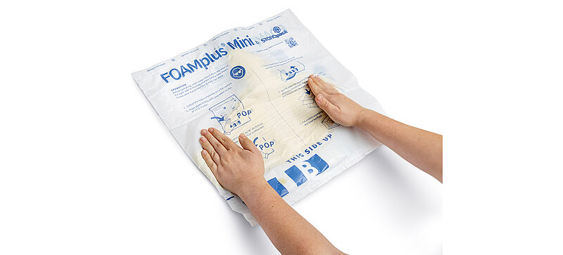 A hand is dispensing foam into a FOAMplus Mini cushion