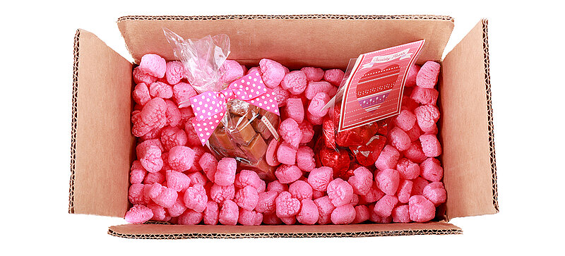 Ein Karton mit Süßigkeiten und pinkfarbenen herzförmigen Verpackungschips