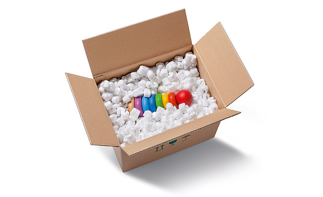 Im Karton ist ein Kleinkindspielzeug, das umgeben ist von weißen S-förmigen Verpackungschips.