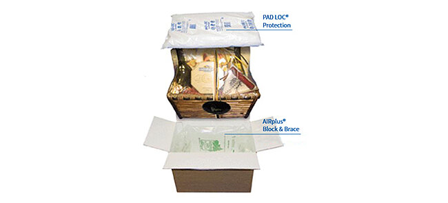 Ein Karton mit einem Geschenkkorb und Luftpolstern und Pelaspan Pac 