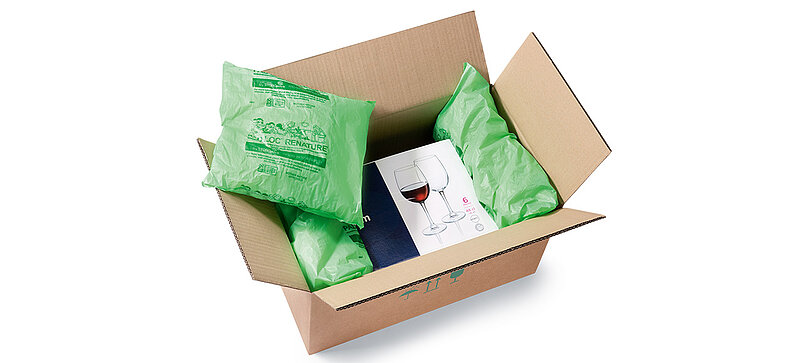 Ein Karton mit einer Box Weingläser gepolstert mit Kunststoffbeuteln mit Verpackungschips